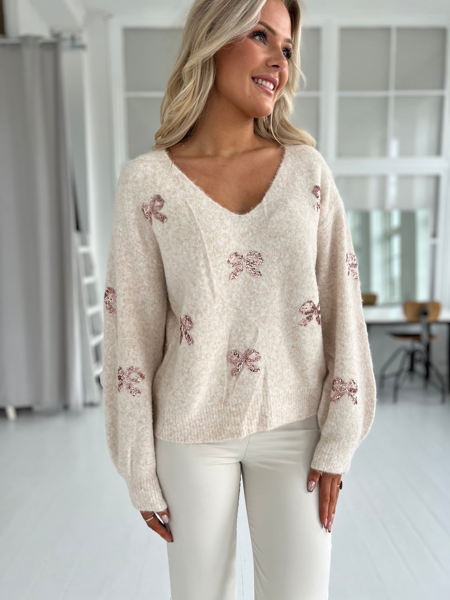 Graciela beige knit (8153) - viser  glitrende pailletsløjfer på forsiden og ærmer - Fra webshoppen Aaberg Copenhagen 